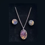 Close-up shot focusing on the oval silver pendant highlighting the intricate purple floral structures and shining gold foil flakes inside the clear resin.