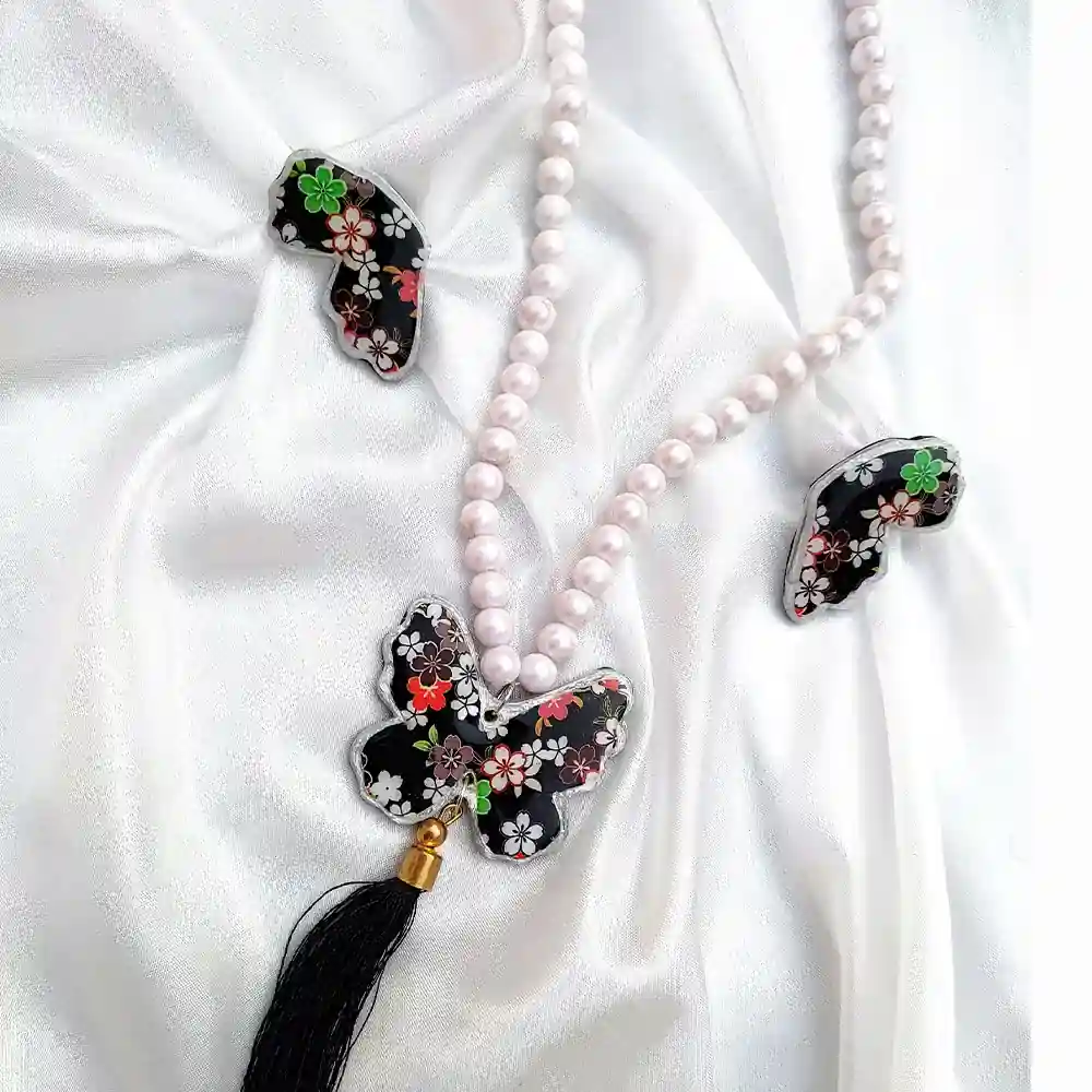 Black resin Butterfly Floral Pearl on white pearls with matching wing earrings on white silk fabric.