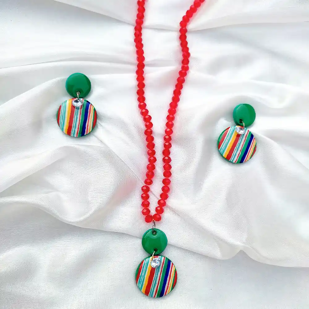 This Multicolor resin and pearl jewelry with red beaded necklace chain with matching drop earrings on draped white silk.