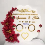 Full view of a curved shape white acrylic thumb impression board with gold lettering and a crescent border of brownish-red-flowers.