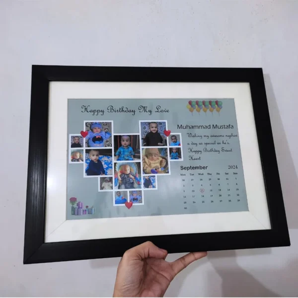 Handheld view of a customized black wall hanging birthday frame with a heart-shaped photo collage and custom text on a green background.