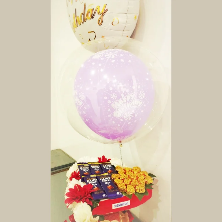 Full view of a heart-shaped chocolate gift basket with a purple happy birthday balloon inside a clear balloon dome.