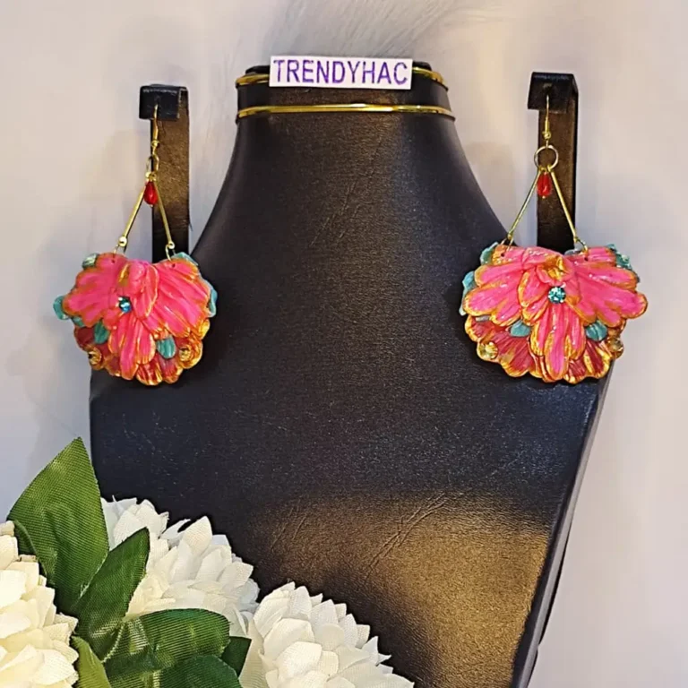 Pair of large fan-shaped hot pink clay floral earrings with gold trim and blue rhinestones displayed on a black neck stand with a TRENDYHAC label.