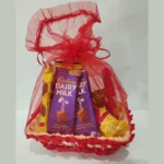Front view of a pink-themed chocolate gift basket with Cadbury Dairy Milk bars wrapped in red organza mesh.