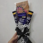 Front view of a mini chocolate bouquet with three Cadbury Dairy Milk bars and a pink and black beaded handmade bracelet.