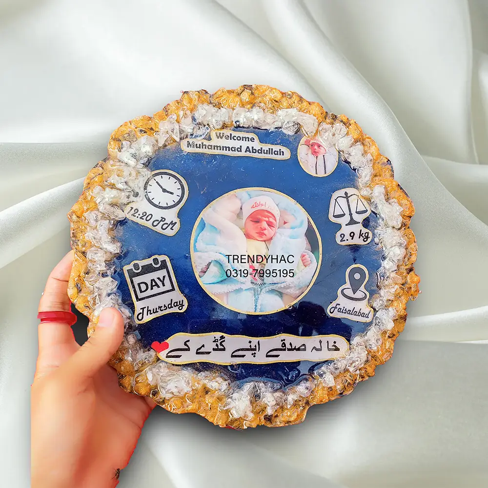Personalised Blue Newborn Baby Resin Plaque Handheld view of a circular blue resin newborn baby plaque with a central photo, birth stats, and a gold crystal geode border.