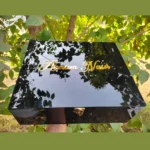 Elegant presentation of a personalized glossy black chocolate gift box styled outdoors.