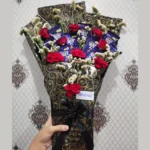 A person holding the custom chocolate and red flower bouquet, showcasing its grand presentation and size.