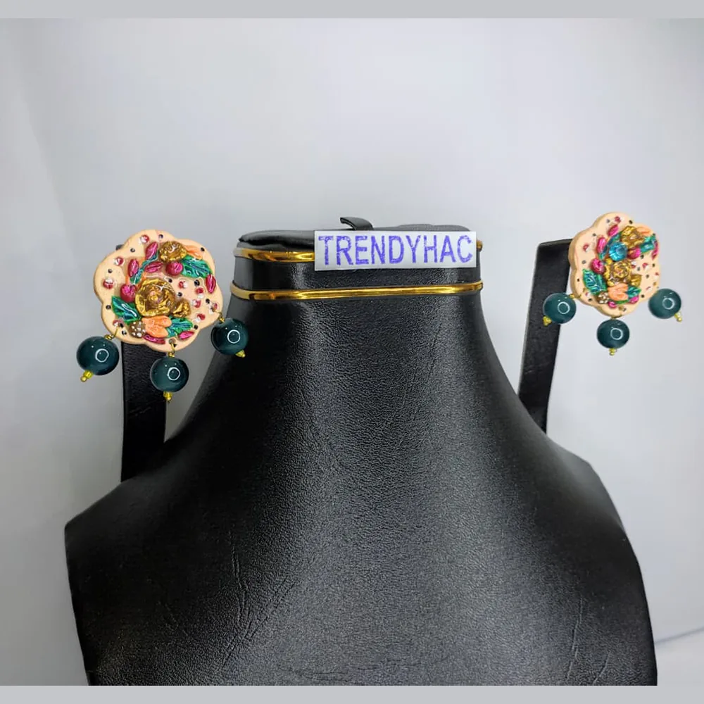 Front studio view of a black display bust showcasing a pair of scalloped cream 3D floral stud earrings with gold roses and dangling dark green beads.