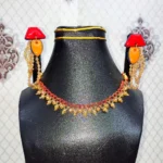 Macro close-up of geometric red and orange clay earrings with hanging gold bead strands and a matching red woven beaded collar necklace on a black bust.