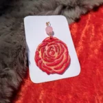 Close-up shot focusing on the sculpted red rose clay petals highlighted with pink accents and shimmering metallic gold paint ridges.