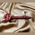 Full view of a customized red resin pencil pen personalized with the name Saba on a gold satin cloth background.