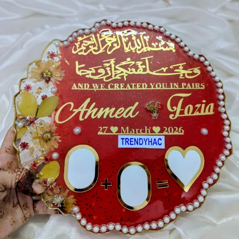 Handheld view of a circular red resin Nikah thumb board with gold calligraphy, names, pearl borders, and signing blocks.