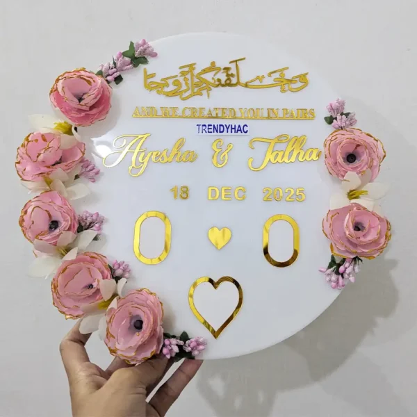Round white acrylic Nikah plaque with pink roses, gold mirrored Arabic calligraphy, and custom couple names.