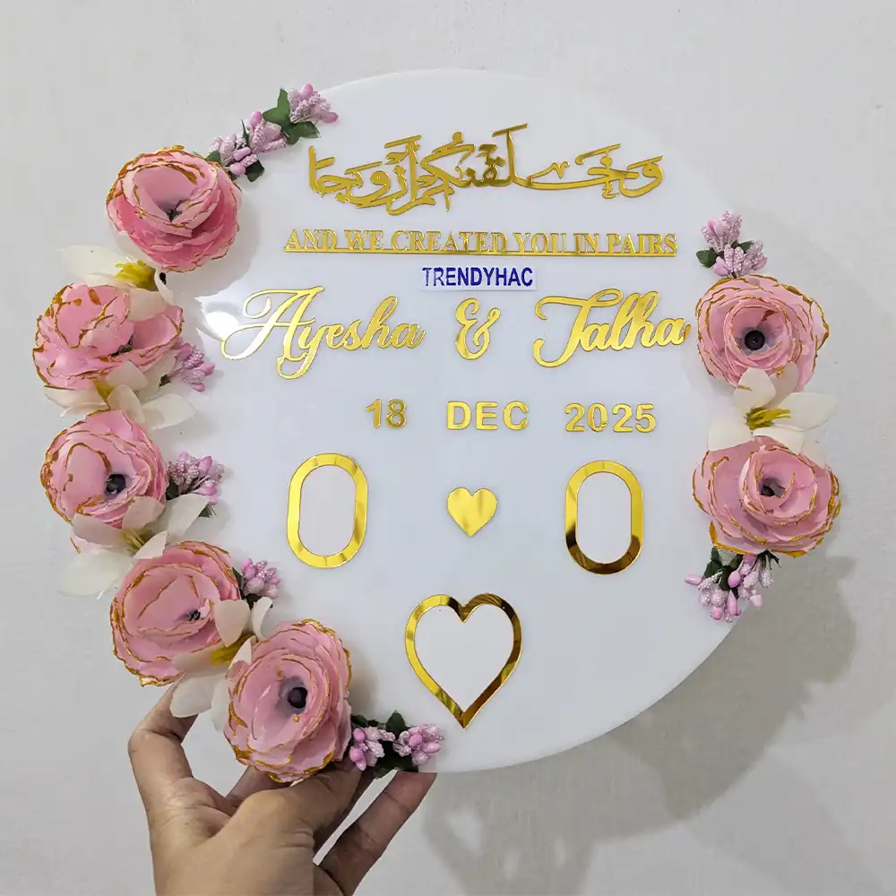 Round white acrylic Nikah plaque with pink roses, gold mirrored Arabic calligraphy, and custom couple names.
