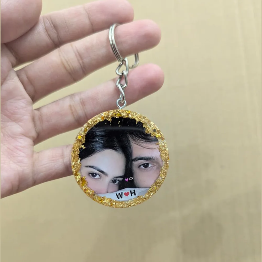 Round customized resin photo keychain featuring a couple photo and gold foil flake border.