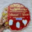 Handheld view of a circular red resin Nikah thumb board with gold calligraphy, names, pearl borders, and signing blocks.