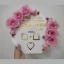 Full view of a hexagonal white acrylic thumb impression board with gold lettering and a crescent border of pink flowers.