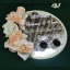 Overhead view of a round mirror acrylic Nikah ring tray featuring white Islamic calligraphy, personalized names, a pearl border, and peach roses.
